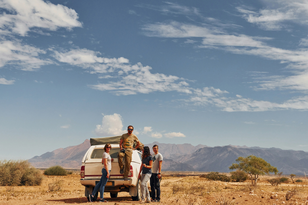 Photographer near car that is in the deserts of Africa, Namibia.