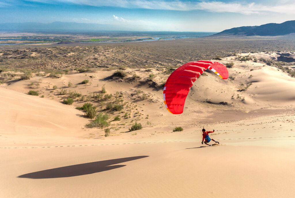 Silhouette of paraglider flying in the dune